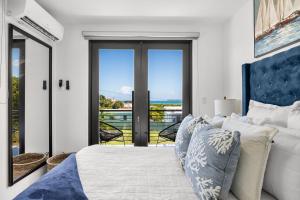 a bedroom with a white bed and a balcony at Casa Blue Laguna II |"Tropical Escape with Ocean Views I Steps to Bio Bay & Seven Seas I Guest Discounts on Boat Tours" in Fajardo