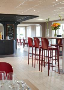 a restaurant with red chairs and tables and a bar at Campanile Montélimar Nord in Les Tourrettes