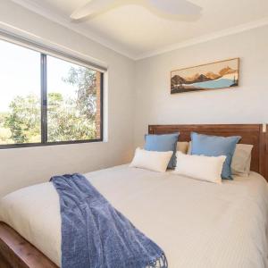 a bedroom with a large bed with blue pillows at Lakeside Breeze in Jindabyne