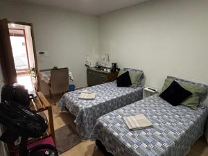 a room with two beds and a table and a chair at Rancho do Viajante Quarto B2 in Castro