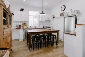 a kitchen with white cabinets and a wooden table with stools at Old Maffra Cottage in Maffra
