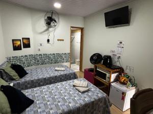 a bedroom with two beds and a fan at Rancho do Viajante Quarto B2 in Castro