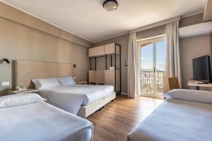 una camera d'albergo con due letti e una televisione di Hotel Pomara a San Michele di Ganzaria Altre 40 foto