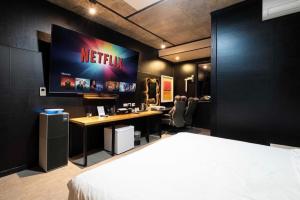 a bedroom with a bed and a desk with a television on the wall at Dalbit Sori Hotel Jeonju in Jeonju