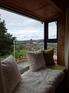 a window seat with a view of a city at Vista volcanes house in Puerto Varas +9 photos