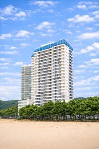 a tall white building with trees in front of it at Yangyang Cohost Studio in Yangyang