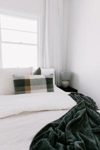 a bedroom with a white bed with a blanket on it at Old Maffra Cottage in Maffra +53 photos