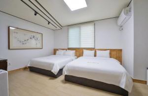 two beds in a room with white walls at Jeonju Dalbitsori Pension in Jeonju