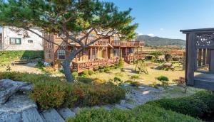a wooden house with a tree in the yard at Buan Pension Maple in Buan