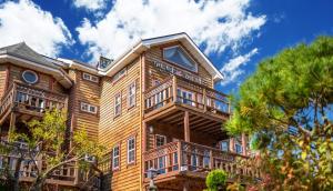 a large wooden house with balconies and trees at Buan Pension Maple in Buan