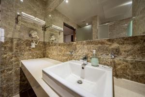 a bathroom with a white sink and a tub at Sunrise Hotel Seongsan in Seogwipo