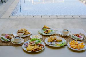 a table with plates of food and cups of coffee at Telaga Village Resort in Pantai Cenang +73 photos