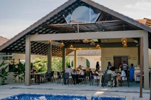 a group of people sitting at tables on a patio at Telaga Village Resort in Pantai Cenang