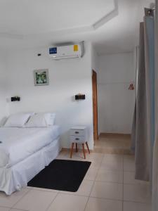 a white bedroom with a bed and a small table at BCHotel in Siguatepeque