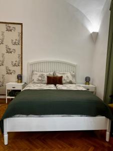 a bedroom with a white bed with a green blanket at Forst Apartman in Eger
