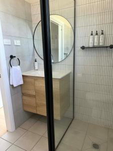 a bathroom with a shower with a mirror and a sink at Units on Robertson in Mudgee +20 photos