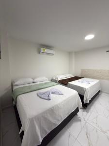 two beds in a room with white walls at Hotel Bello Horizonte in Santa Marta