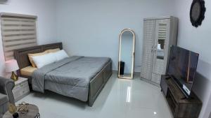 ein Schlafzimmer mit einem Bett, einem Spiegel und einem Fernseher in der Unterkunft Jacob's Place in Abu Dhabi