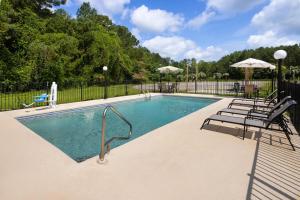 a swimming pool with chairs and an umbrella at Days Inn by Wyndham Hardeeville Near Hilton Head in Hardeeville