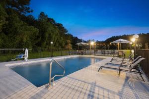 a swimming pool with chairs and umbrellas at night at Days Inn by Wyndham Hardeeville Near Hilton Head in Hardeeville +68 photos