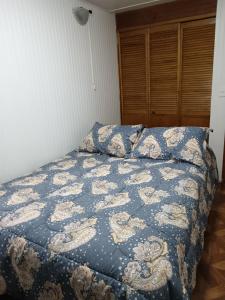 a bedroom with a bed with a blue comforter at Eluney 3 in Valdivia