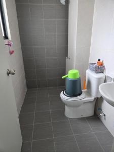 a bathroom with a toilet with a green bucket on it at D'BROGA HILL Homestay in Kampong Solok