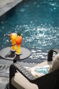two drinks on a table next to a swimming pool at Narci Resort Tam Coc in Ninh Binh