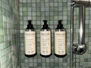 three shampoo bottles on a wall in a bathroom at Lilium Boutique Hotel in Rome