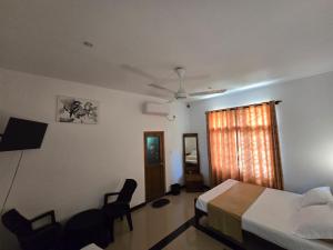 a bedroom with a bed and two chairs and a window at Elephant safari Lodge sigiriya junction in Habarana