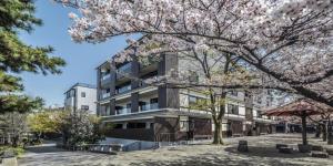 an apartment building with aakura tree in front of it at Hotel Alza Kyoto in Kyoto