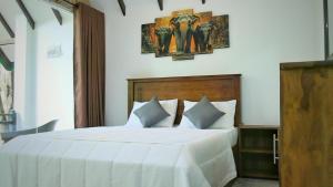 a bedroom with a white bed with two elephants on the wall at Ranthilaka Villas in Kandy