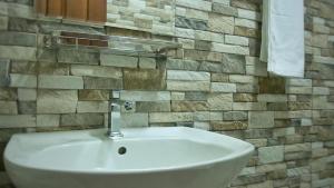 a white sink in a bathroom with a stone wall at Ranthilaka Villas in Kandy