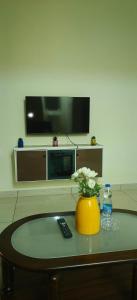 a living room with a tv and a vase with flowers on a table at Hangang M building in Avati