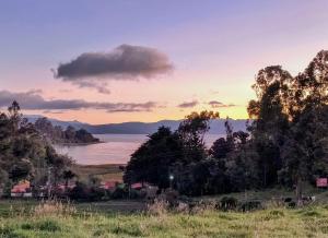 a sunset over the water with trees in a field at Chalet Stonehenge in Pasto