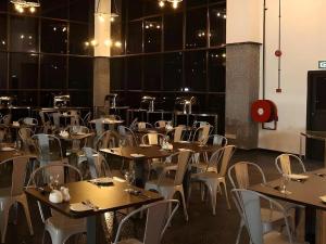 a dining room with tables and white chairs at Arafah Hotel Nilai in Kampong Tanjong
