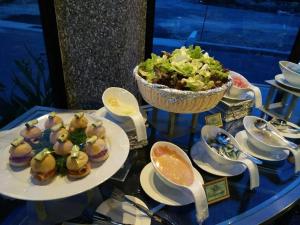 a table with plates of food and a bowl of salad at Arafah Hotel Nilai in Kampong Tanjong