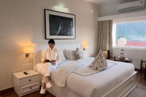 a woman sitting on a bed looking at a cell phone at Sanskriti Vedic Retreat in Rishīkesh +31 photos