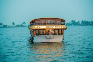 a boat in the water with a sign on it at My Trip Houseboats in Alleppey