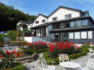 a house with a garden with red flowers and a fountain at Damson Dene Hotel in Bowness-on-Windermere