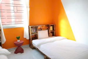 a bedroom with orange walls and a bed and a window at Mocha Vila Mộc Châu in Mộc Châu +4 photos