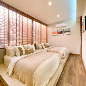 two large beds in a bedroom with windows at Swan Private Pool Villa Bangsaen in Ban Thai Don (1) +17 photos