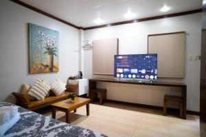 a room with a tv and a couch and a bed at Madonna Hometel and Suites in Panabo