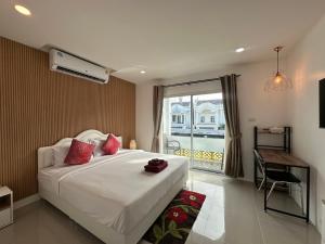 a bedroom with a bed with red pillows and a window at Inn Dulgence in Patong Beach
