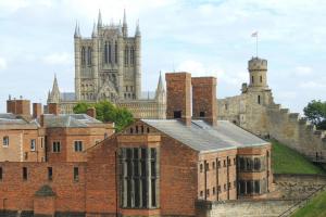 an old brick building with a cathedral in the background at Garner Hotel Lincoln by IHG in Lincoln