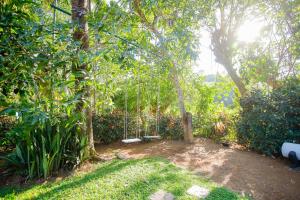 a garden with a swing in the trees at Cinnamon Legacy in Weligama