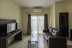 a living room with a couch and a television at Daffodil Suites, Manyata Tech Park, Bengaluru in Bangalore