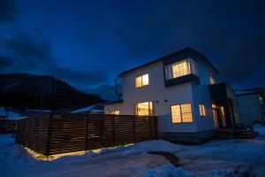 a house with lights on in the snow at night at 禅ーZen Villa Hakodate in Hakodate