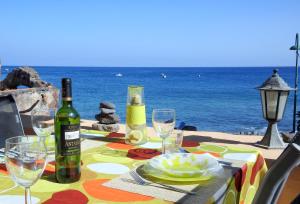 a table with a bottle of wine and glasses on the beach at La Casita de la Playa in Igueste