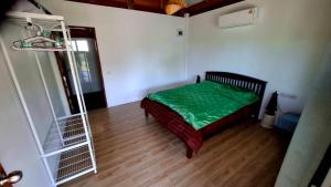 a bedroom with a bed with a green comforter and a ladder at Anna Garden Homestay in Ban Phlu Kom