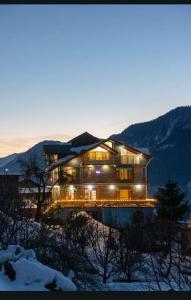 a large house with lights on in the snow at Manali Parvat View in Jagatsukh